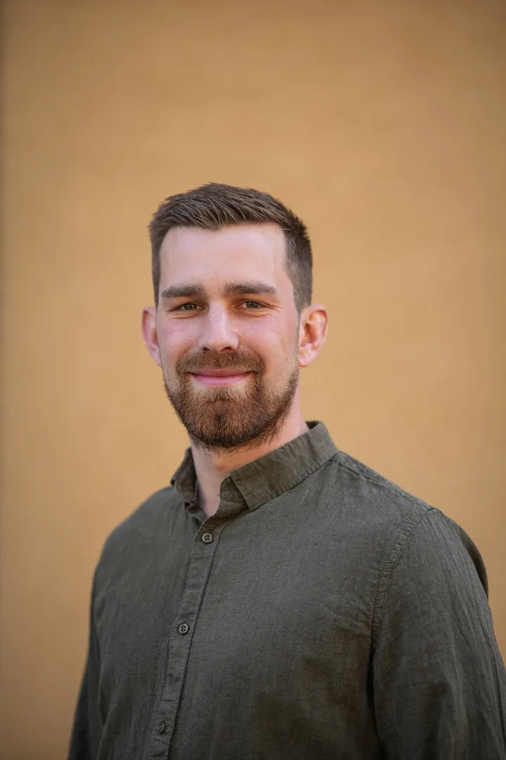 Kevin Grüter im Porträt vor einer ockerfarbenen Wand