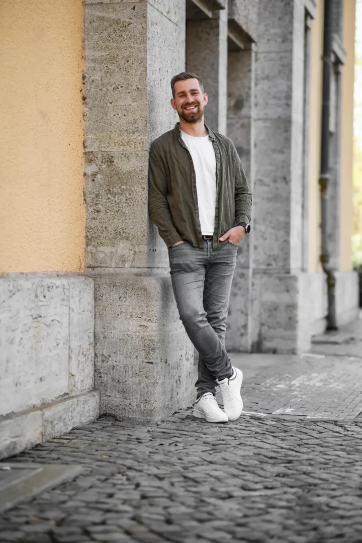 Kevin Grüter im Porträt vor einer ockerfarbenen Wand